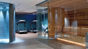 A modern fitness center with treadmills and a glass wall separating the area.