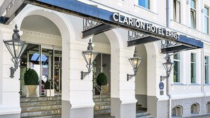 The Clarion Hotel Ernst entrance with a grand archway, steps, and decorative street lamps.