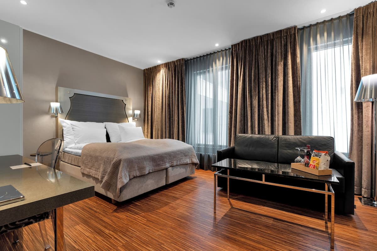 Ein modernes Hotelzimmer mit Bett, Sofa, Couchtisch und Schreibtisch.
