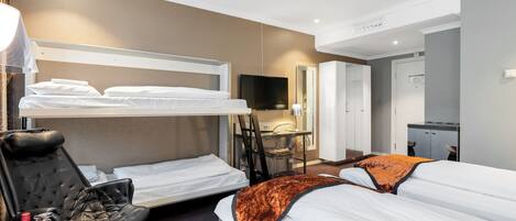 Habitación de hotel con literas, un escritorio con silla, televisión y armario.