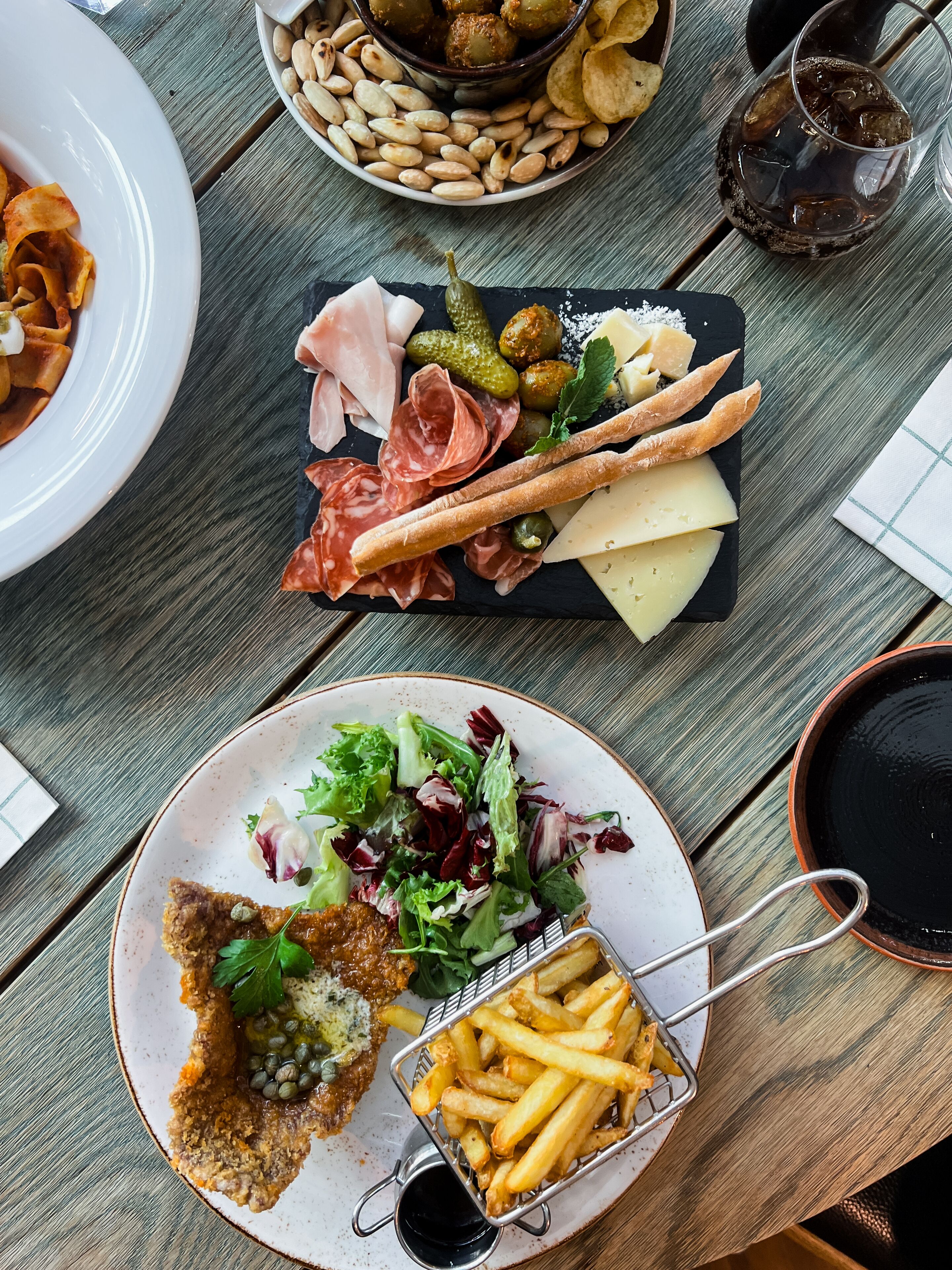A table with various food items including pasta, cheese, pickles, olives, and breadsticks.