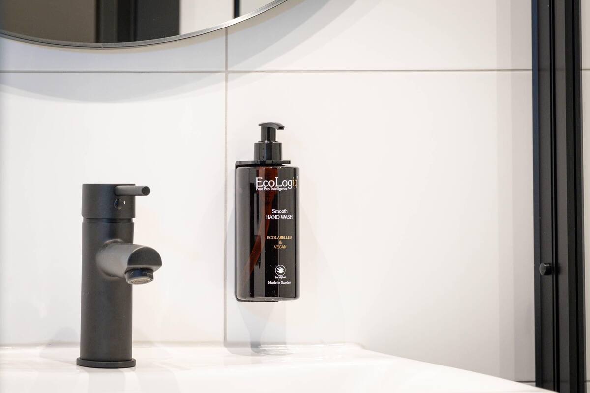 A bathroom with a modern faucet and a bottle of EcoLogic hand wash.