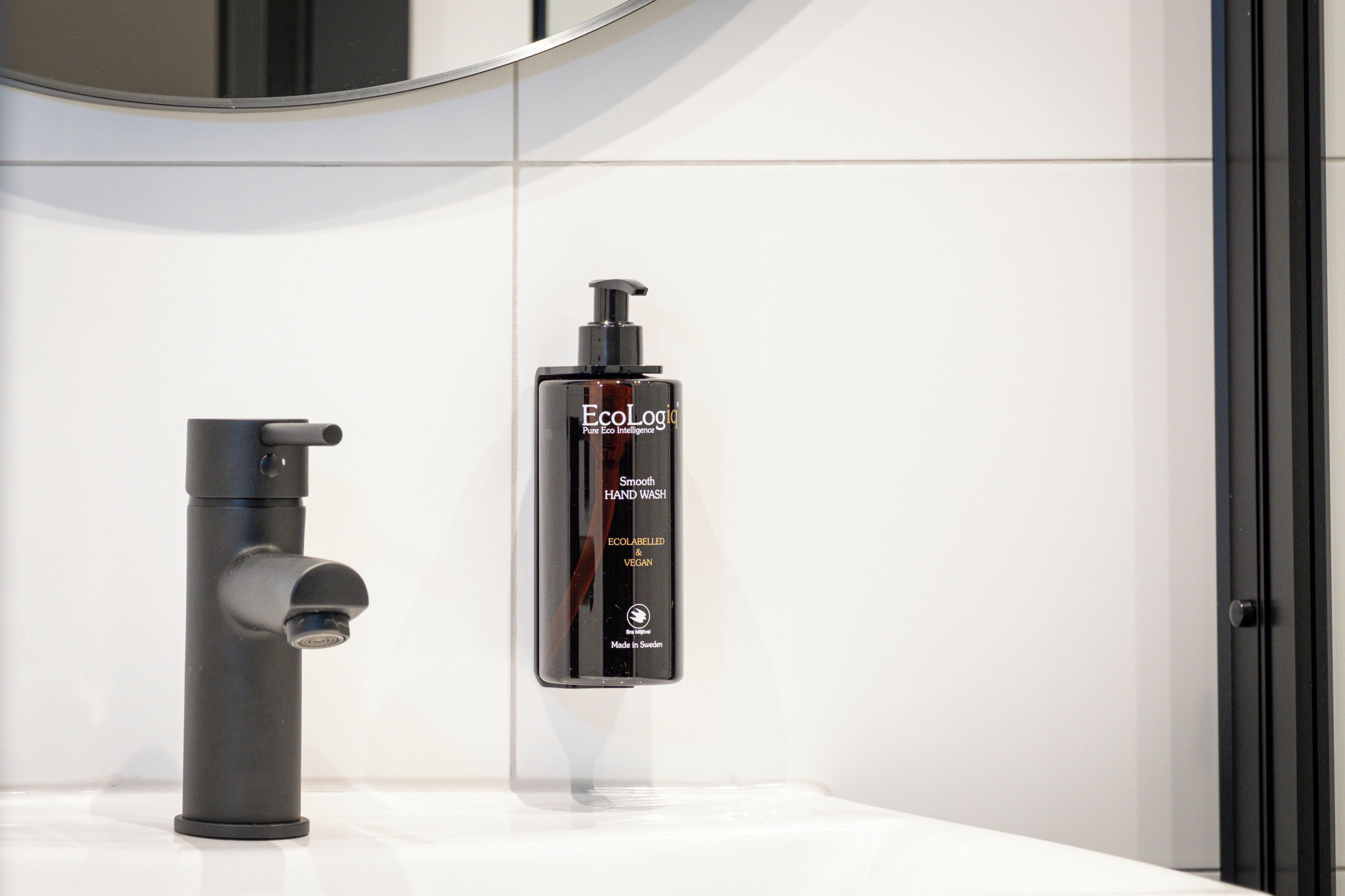 A bathroom with a modern faucet and a bottle of EcoLogic hand wash.
