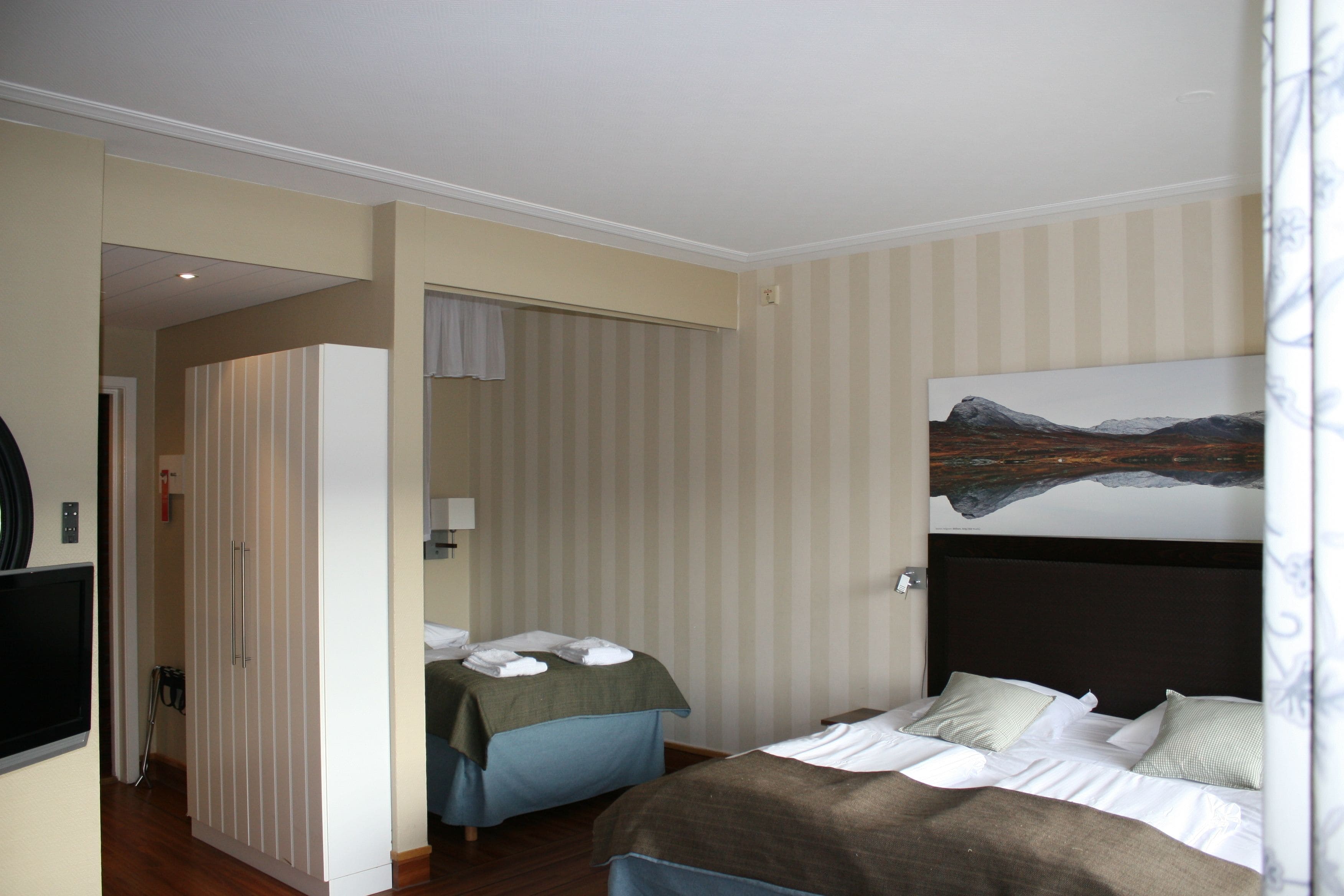 Une chambre d’hôtel avec un lit, un bureau et un tableau au mur.