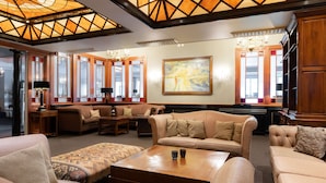 A spacious lounge area with multiple seating options, including sofas and armchairs, a coffee table, and a large painting on the wall. - Scandic Valdres (Nord-Aurdal)