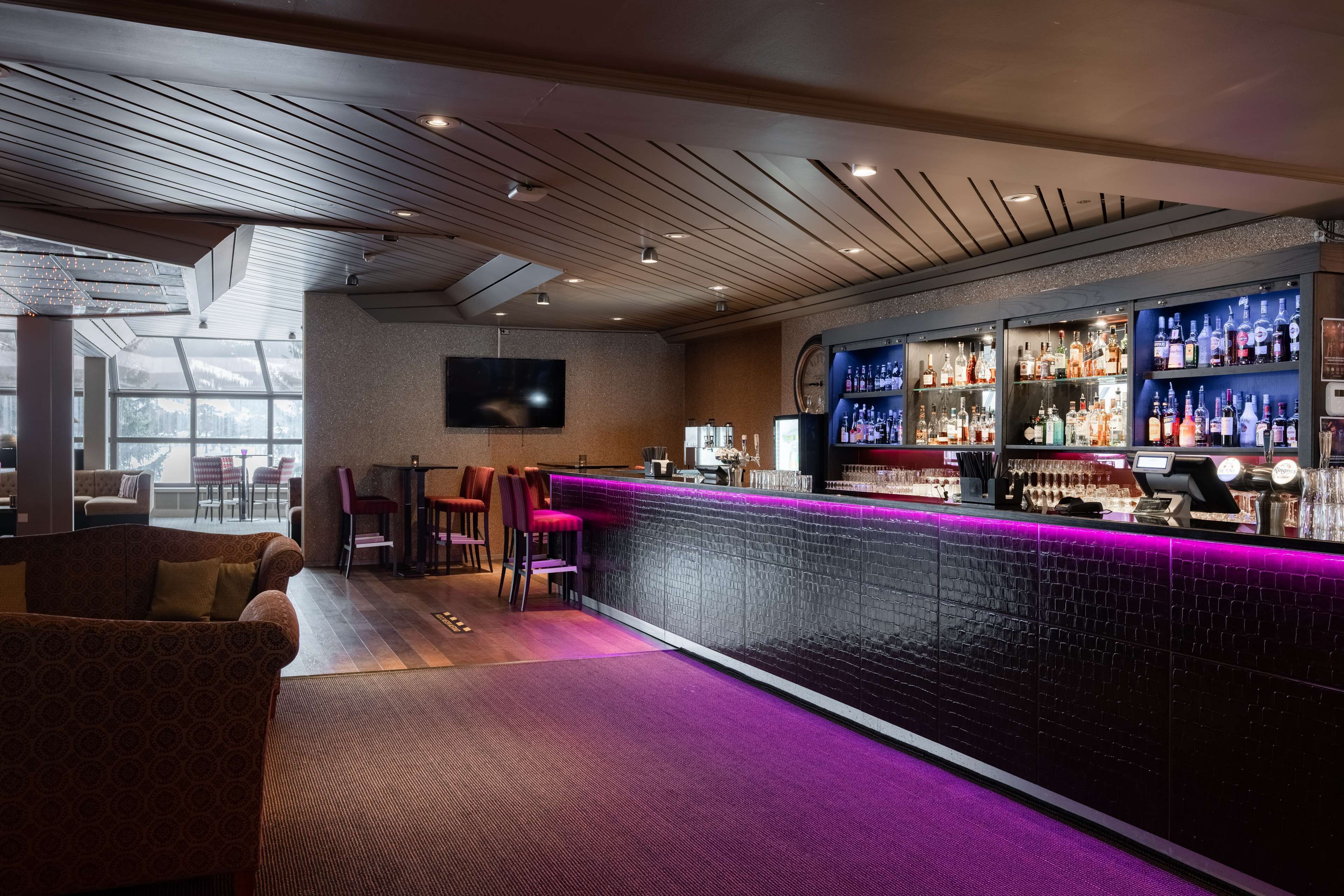 A bar area with a counter, seating, and a television.