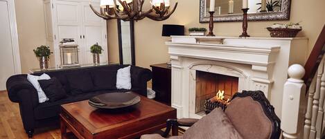 A living room with a fireplace, a sofa, a coffee table, and a chandelier.