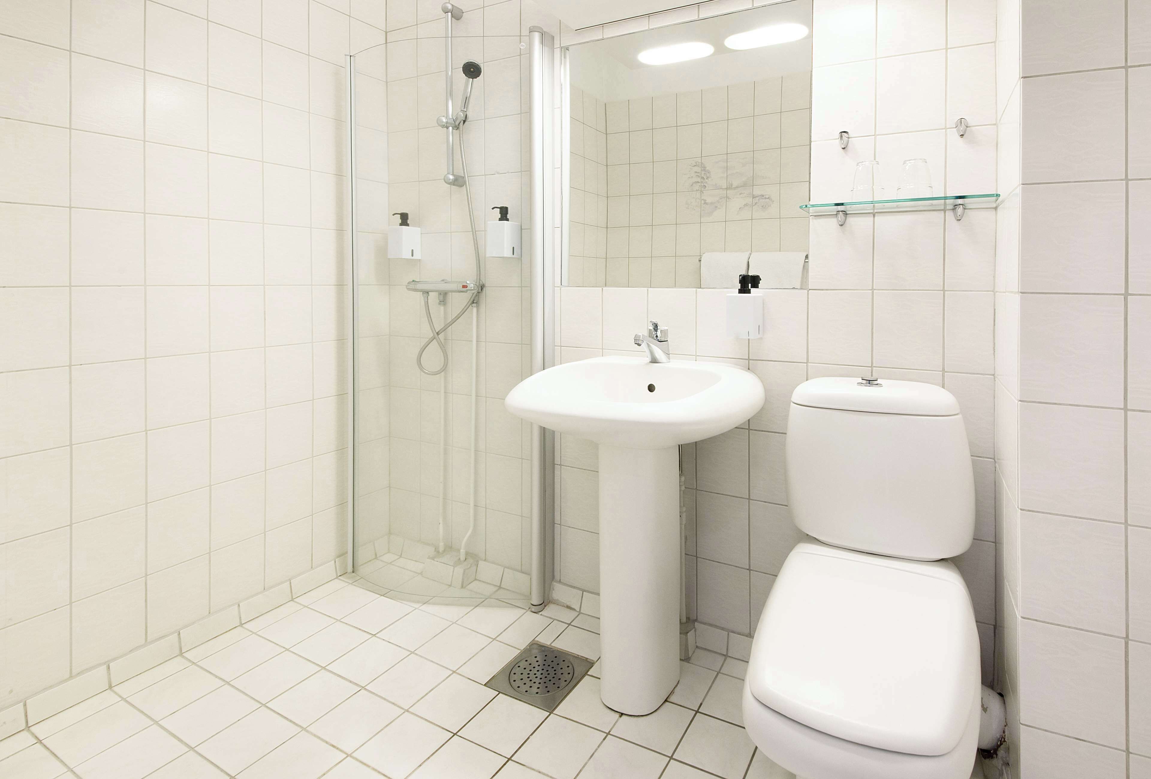 Un baño moderno con cabina de ducha de vidrio, lavabo pedestal y inodoro.