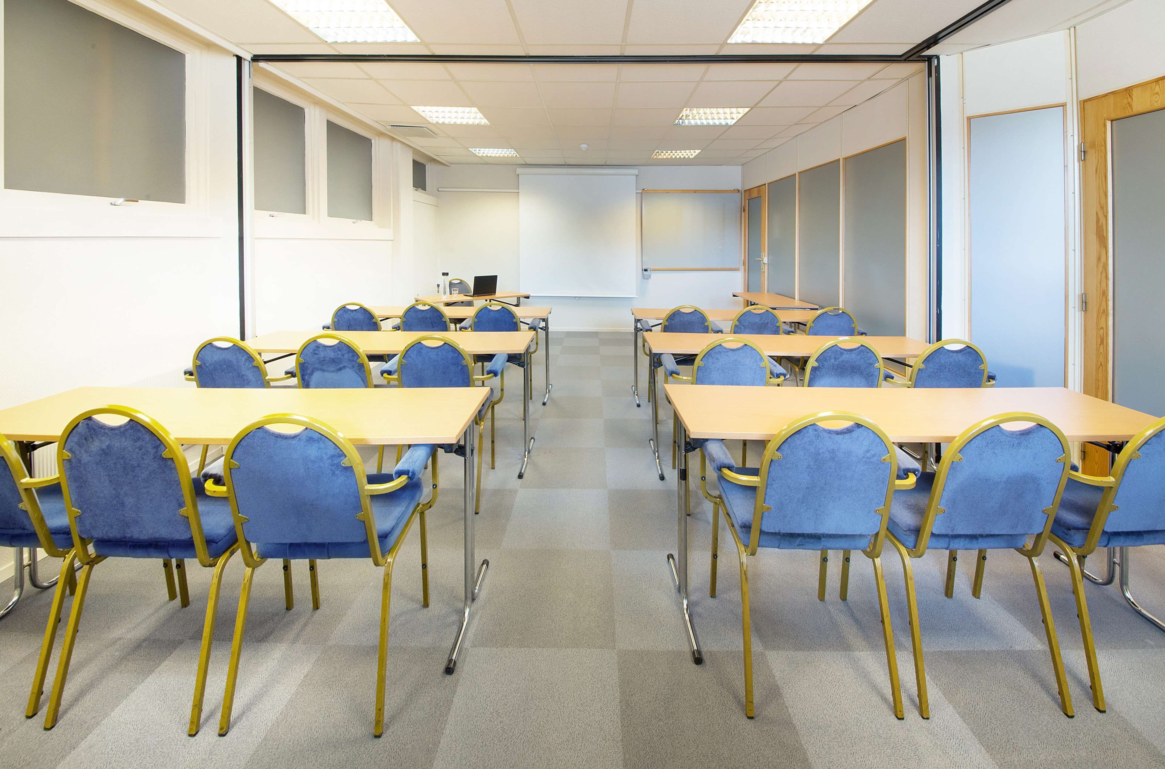 Un salón de conferencias con mesas y sillas dispuestas para reuniones.