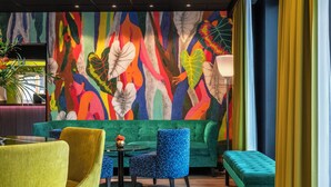 A vibrant lounge area with a colorful abstract mural, a green sofa, a blue armchair, and a yellow chair. - Thon Hotel Slottsparken (Oslo)