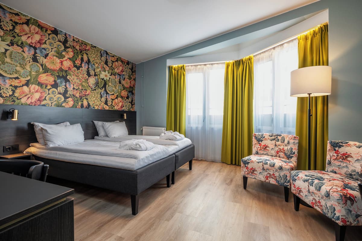 Una habitación de hotel con cama, escritorio, silla y lámpara.