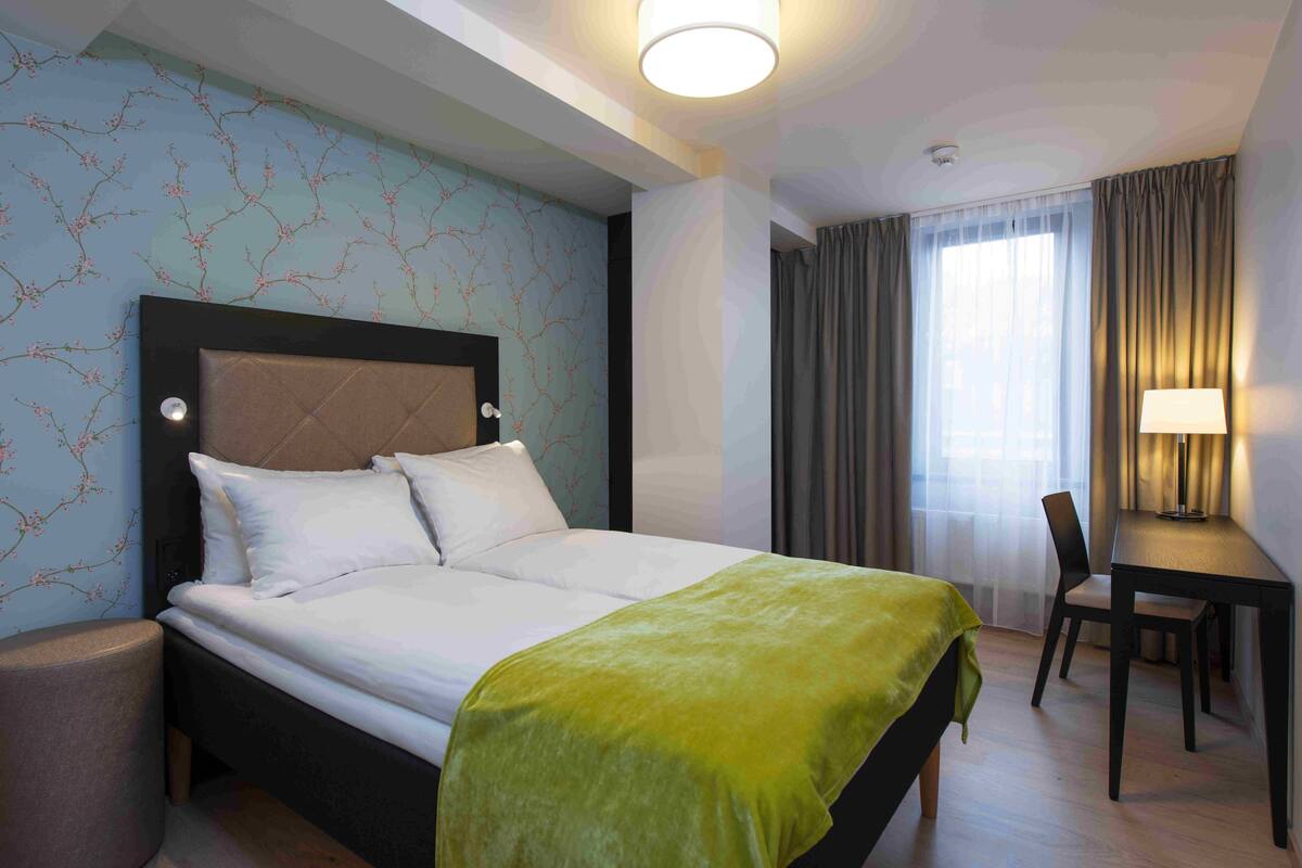 Ein Hotelzimmer mit Bett, Schreibtisch und Stuhl.