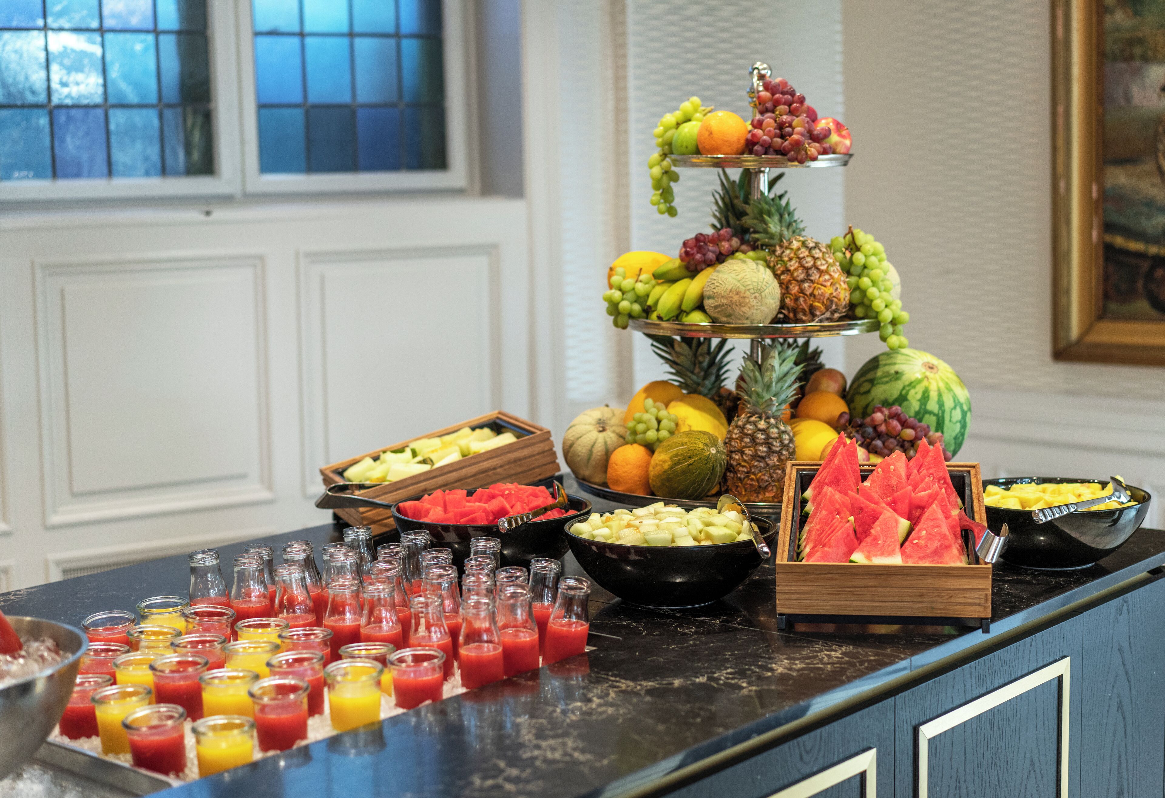 A buffet with various fruits, vegetables, and beverages.