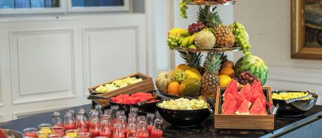 A buffet with various fruits, vegetables, and beverages.