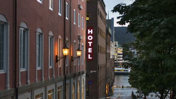 A hotel building with a red facade, large windows, and a sign that reads "HOTEL".