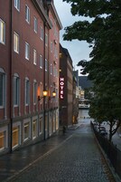 Un edificio de hotel con fachada roja, ventanas grandes y un cartel que dice "HOTEL".
