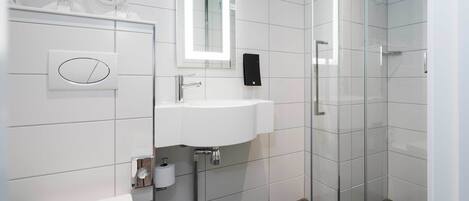 Un baño moderno con ducha de vidrio, lavamanos blanco y retrete.