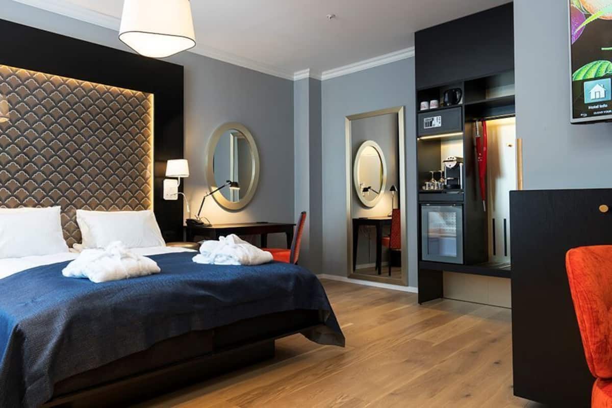Una habitación de hotel con una cama grande, un escritorio, una silla, un espejo y un televisor.