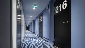 A hotel hallway with a zebra-patterned carpet, doors numbered 215 and 216, and a ceiling with recessed lighting. - Thon Hotel Spectrum (Oslo)