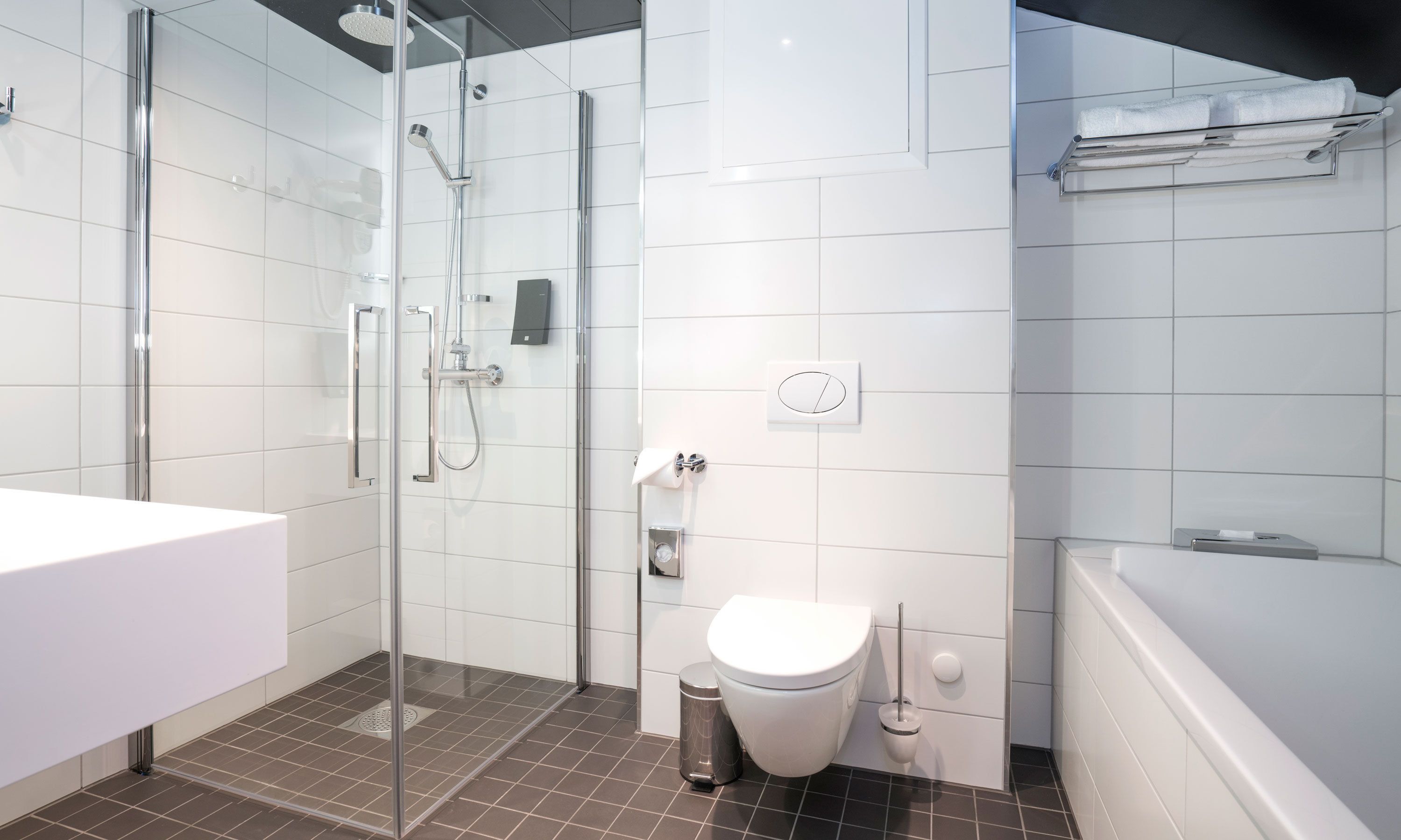 A modern bathroom with a glass-enclosed shower, a white sink, a toilet, and a bathtub.
