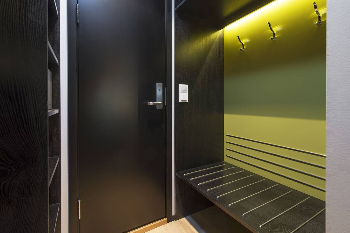 Un ascensor moderno con barandilla metálica y pared verde.