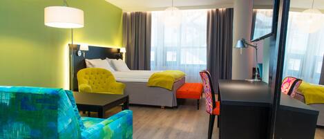A hotel room with a bed, a desk, a chair, and a sofa.