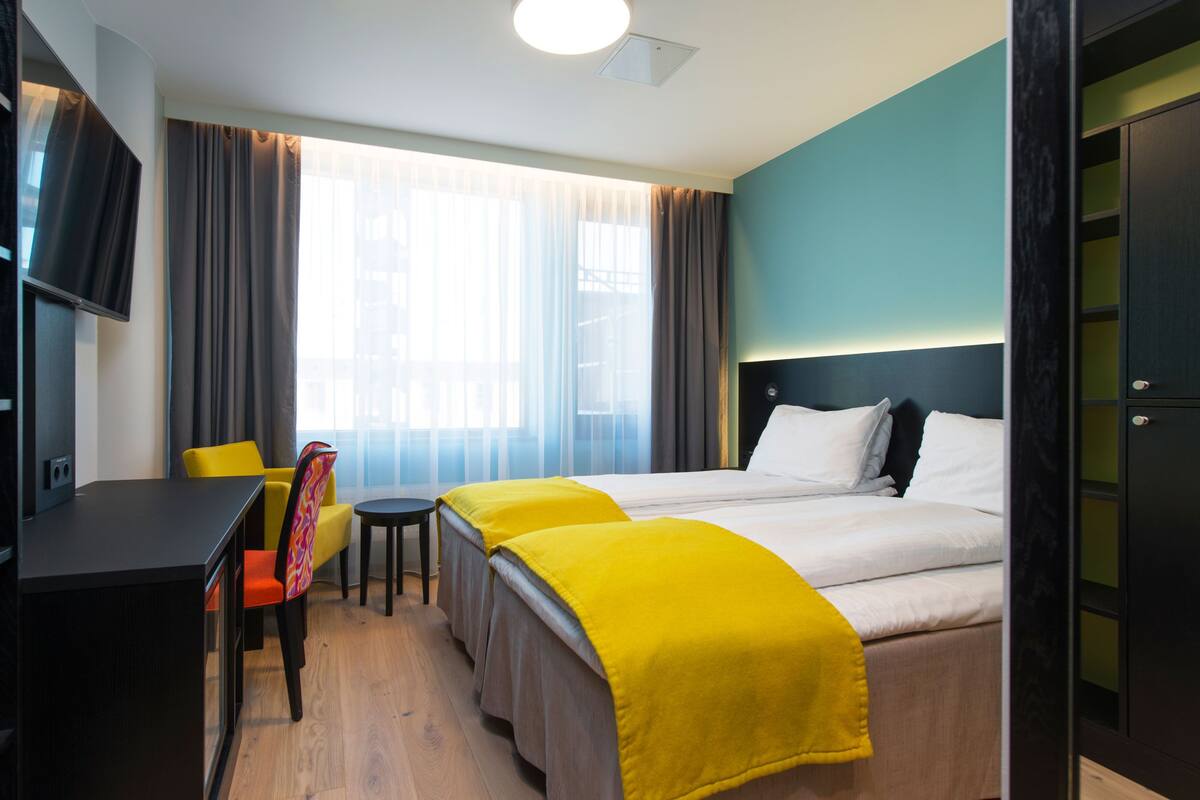 A hotel room with a bed, a desk, a chair, and a television.
