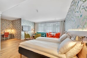 A hotel room with a large bed, a desk, a chair, a sofa, and a table.