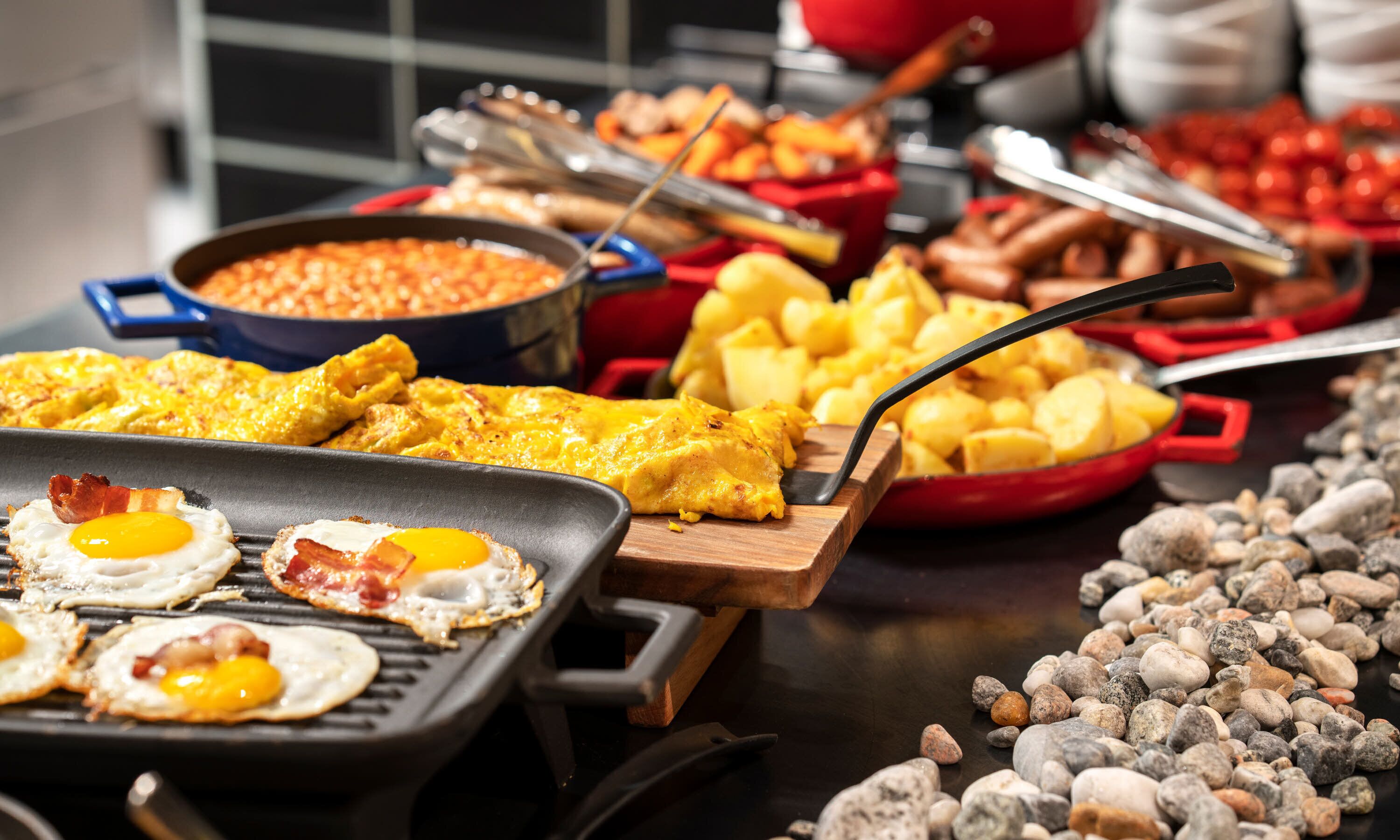 A buffet with various breakfast items including eggs, potatoes, and a casserole dish.
