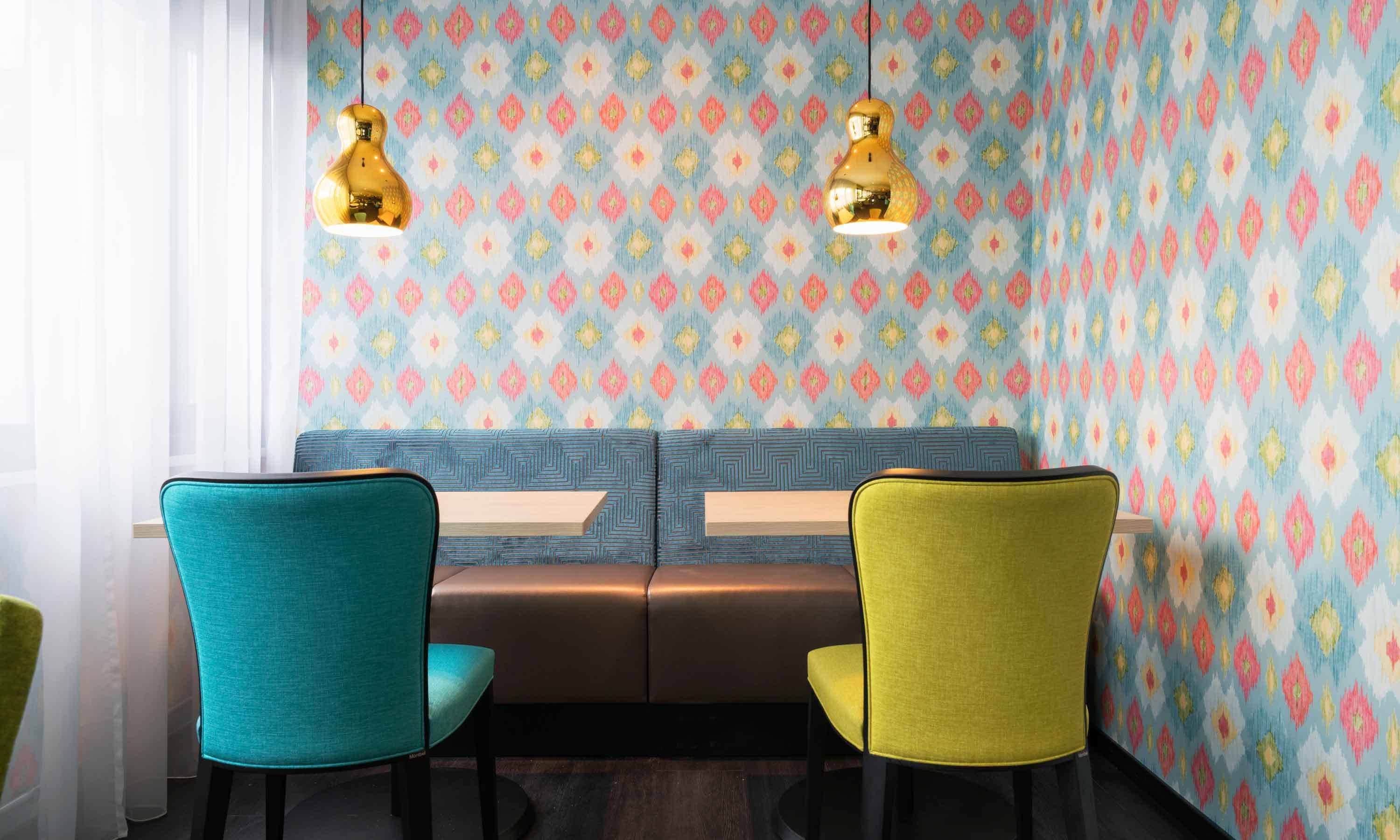 Una habitación con papel tapiz estampado, un sofá y dos sillones.