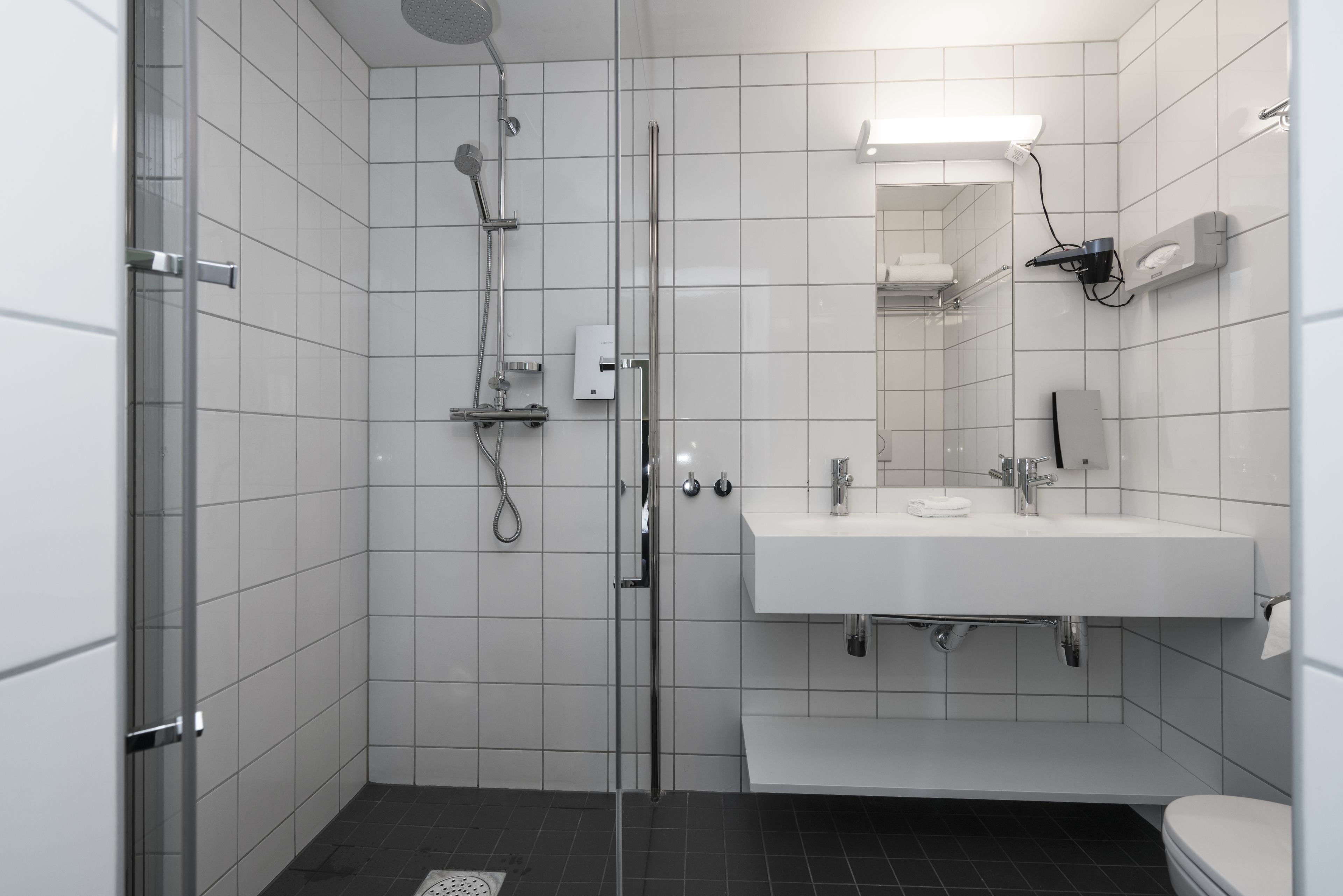 Un baño moderno con cabina de ducha de vidrio, un lavabo blanco y un espejo sobre el lavabo.