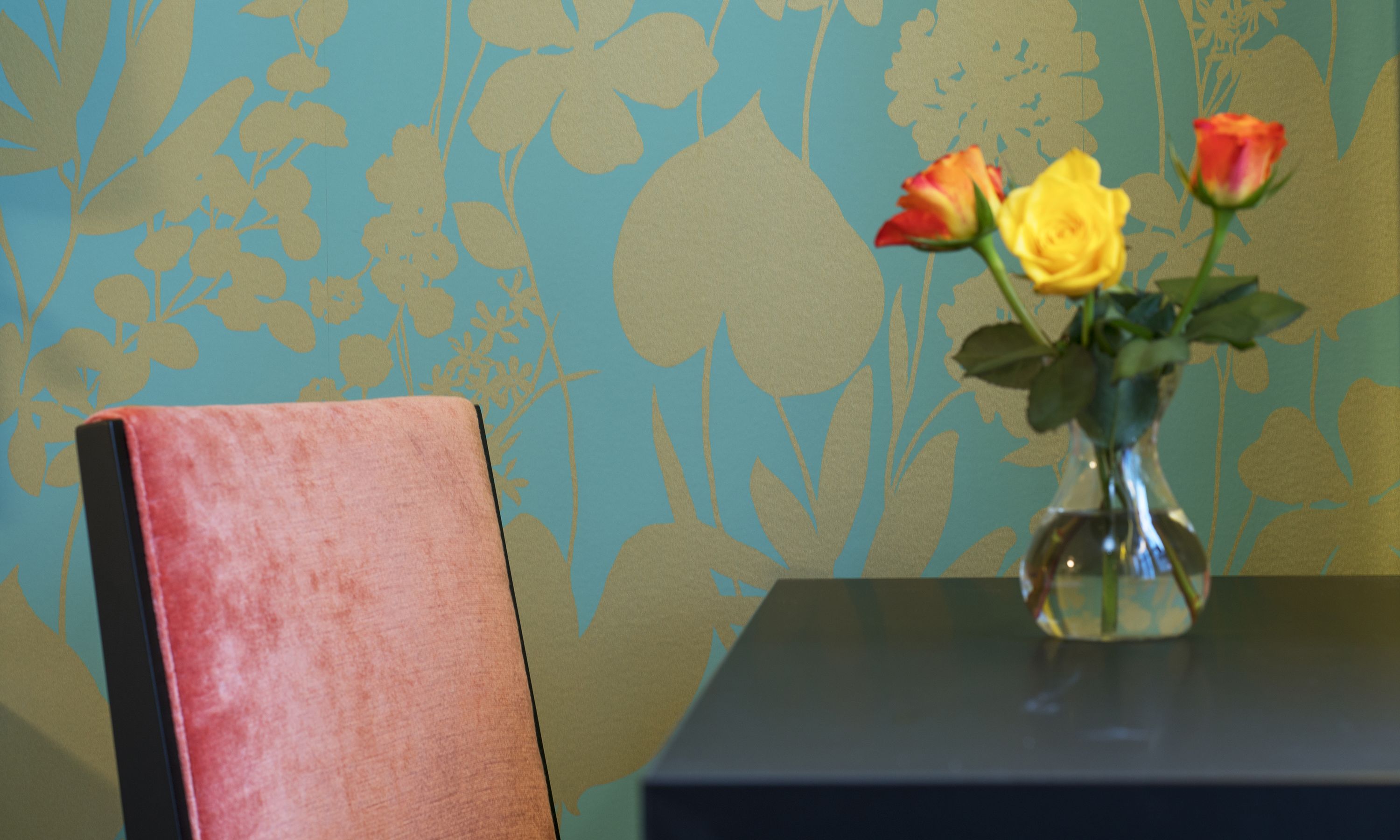 A table with a vase containing flowers and a chair.