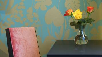 A table with a vase containing flowers and a chair.