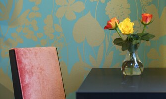 A table with a vase containing flowers and a chair.