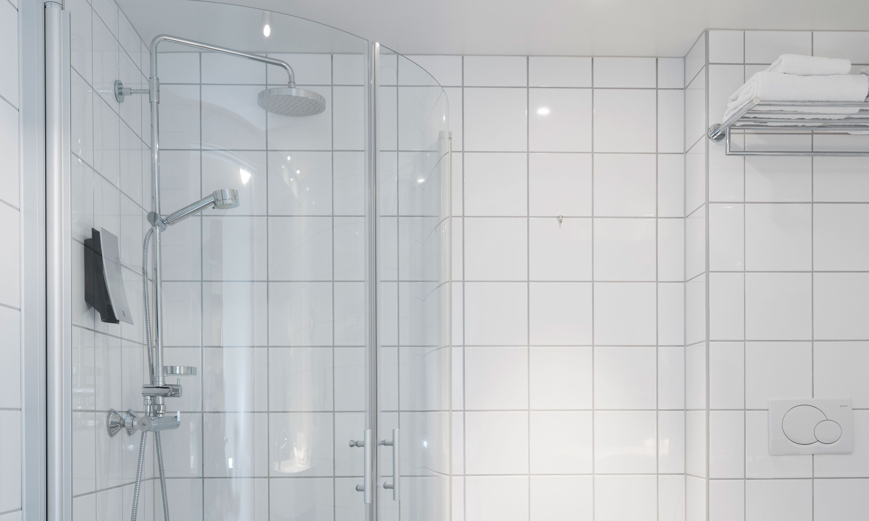 A modern bathroom with a glass-enclosed shower, a towel rack, and a control panel.