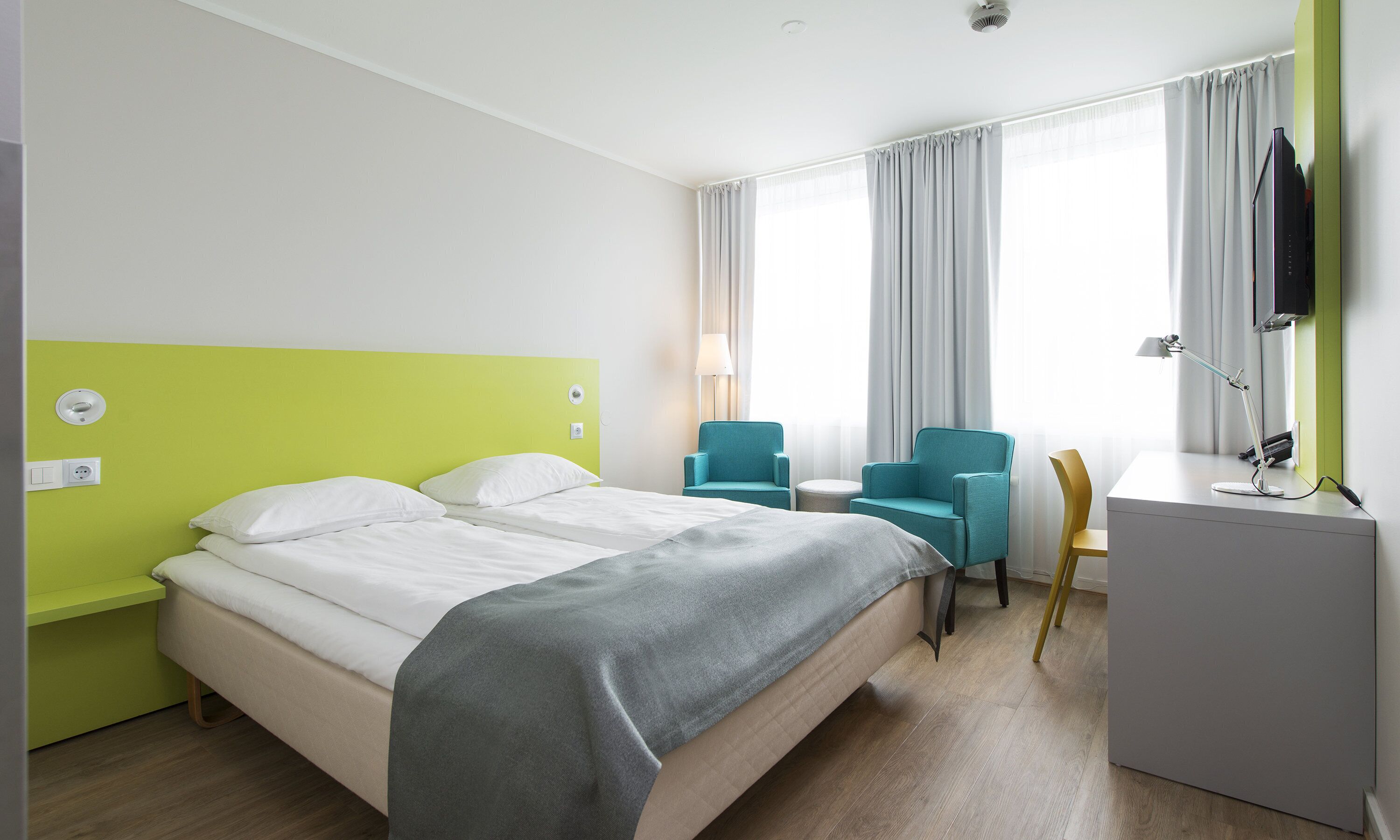 Una habitación de hotel con una cama, dos sillas, un escritorio y un televisor.