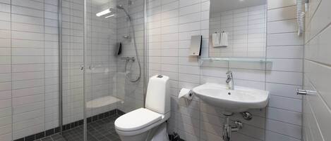 A modern bathroom with a glass shower enclosure, a white toilet, a sink with a mirror above, and a glass shelf.