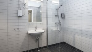 Un baño moderno con cabina de ducha de vidrio, un lavabo blanco y un espejo.