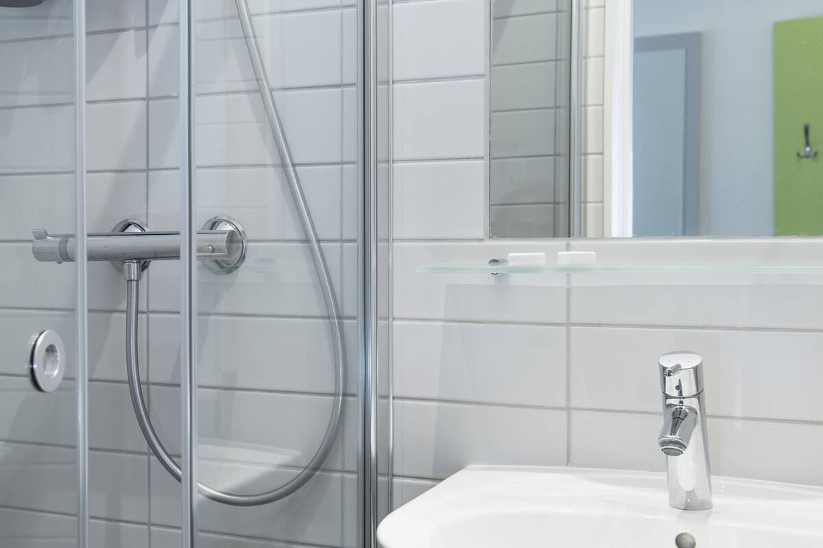 A bathroom with a glass-enclosed shower, a white sink, and a mirror above the sink.