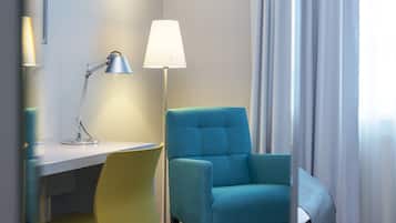A room with a desk, a chair, a lamp, and a window with curtains.