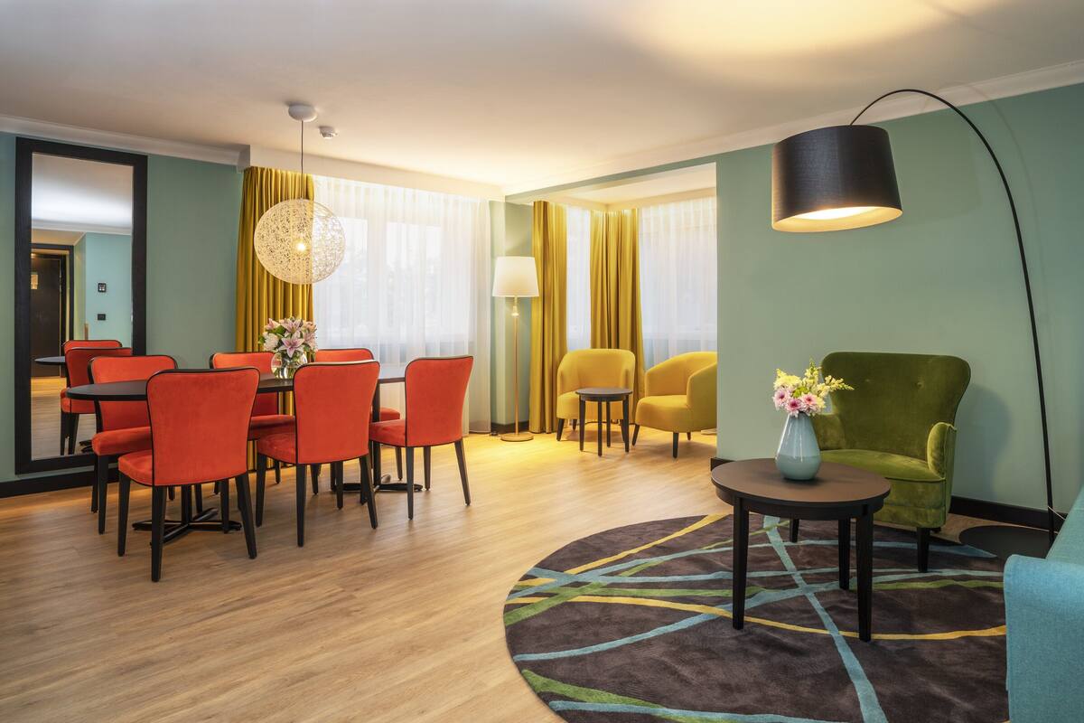 A modern hotel room with a dining area, a sofa, and a coffee table.