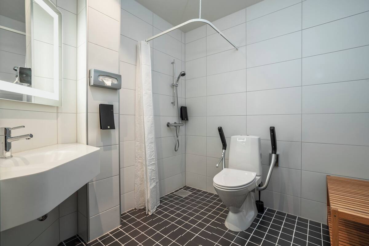 A modern bathroom with a shower, toilet, sink, and a mirror.