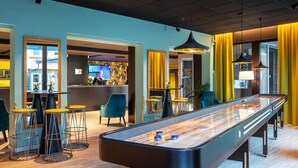 Zona de bar moderna con mesa de billar, taburetes y mostrador de recepción.