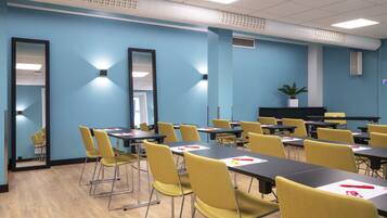 A conference room with tables and chairs, a large mirror, and a plant on a shelf.