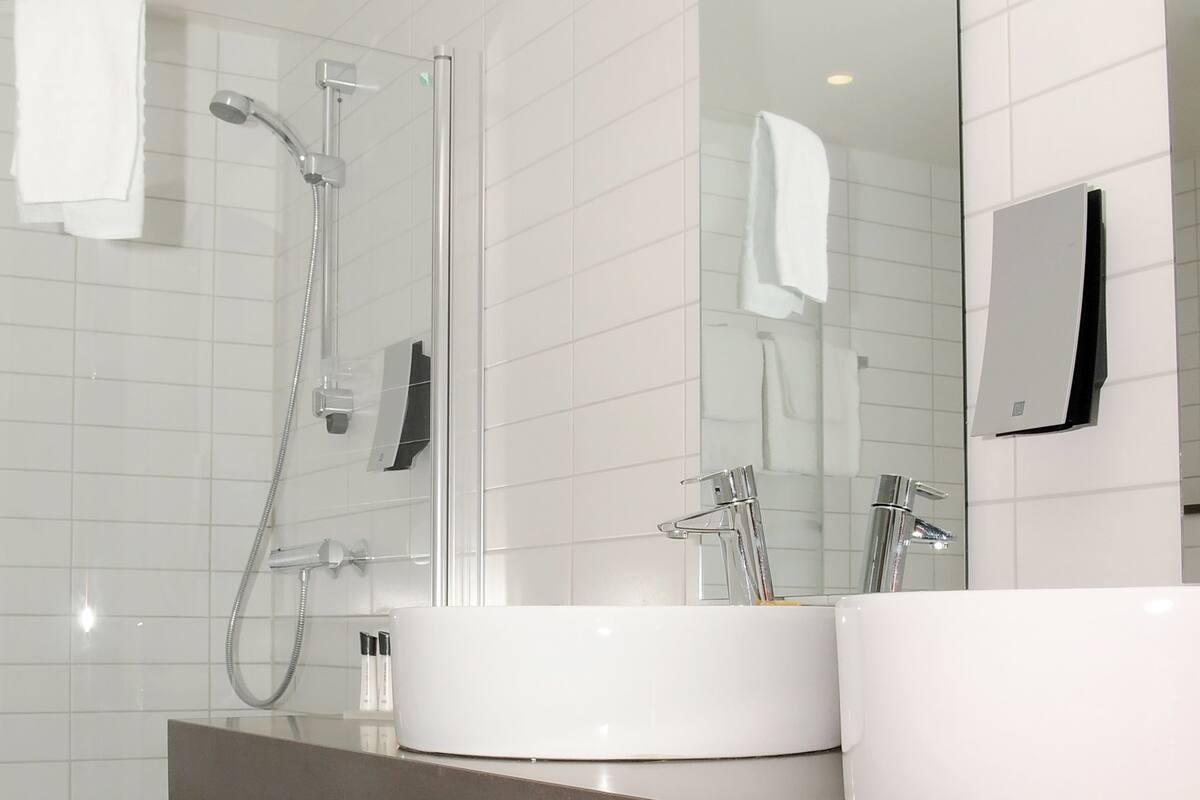 A modern bathroom with a glass-enclosed shower, a white sink, and a mirror.