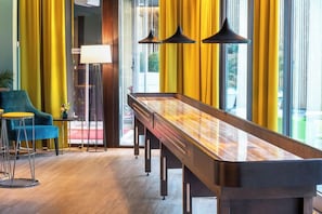 A pool table in a room with yellow curtains, a blue chair, and a lamp. - Thon Hotel Maritim (Stavanger)