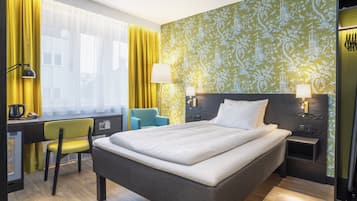 Habitación de hotel con cama, escritorio, silla y dos lámparas de noche.