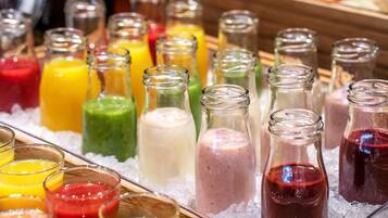 A variety of colorful beverages in glass bottles and glasses, displayed on a bed of ice.