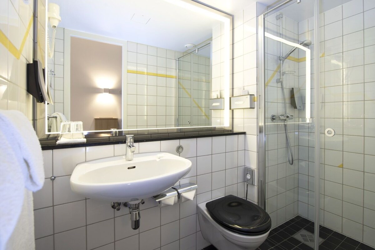 A bathroom with a white sink, mirror, and a glass-enclosed shower.