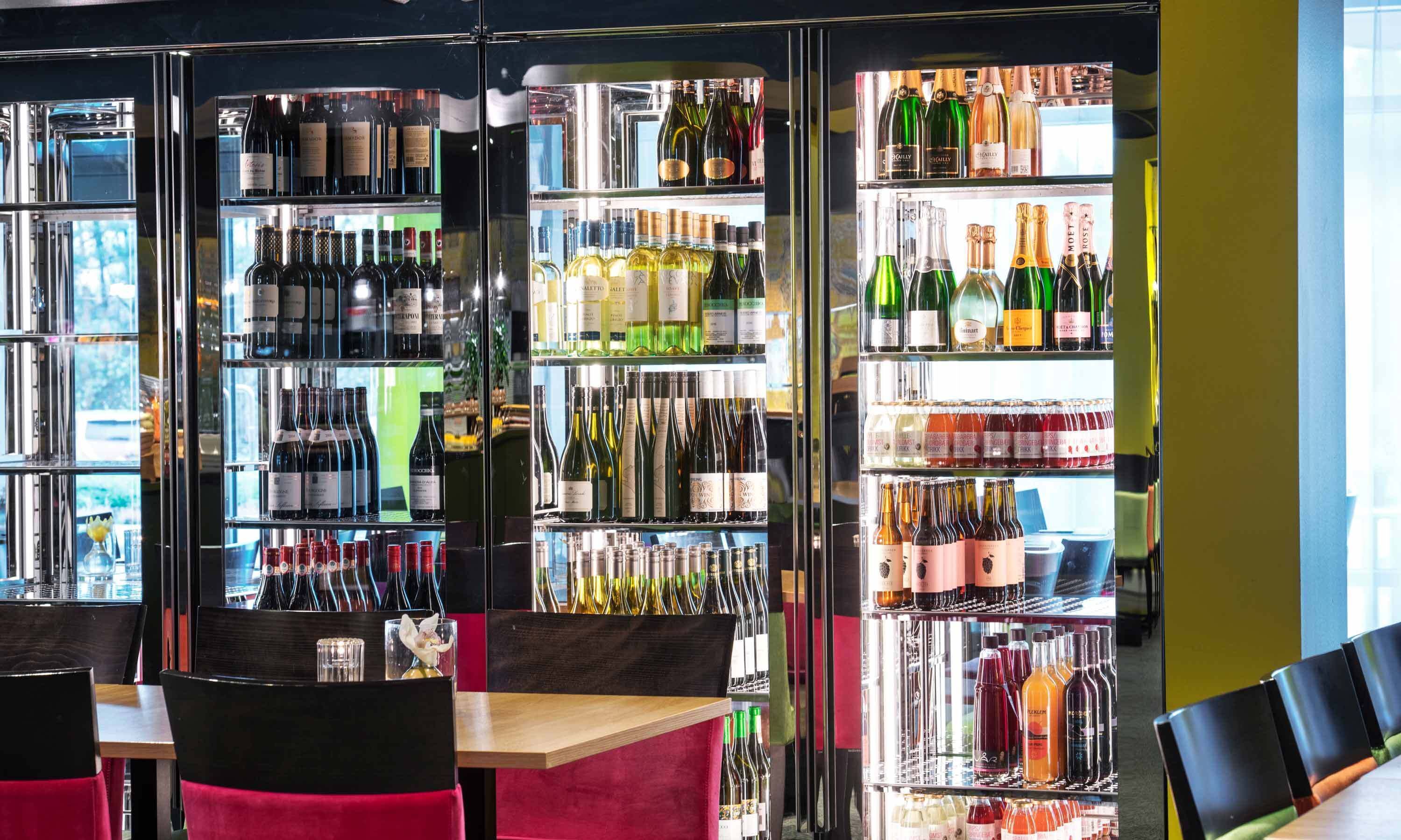Una zona de bar con varias estanterías llenas de botellas de vino y copas.